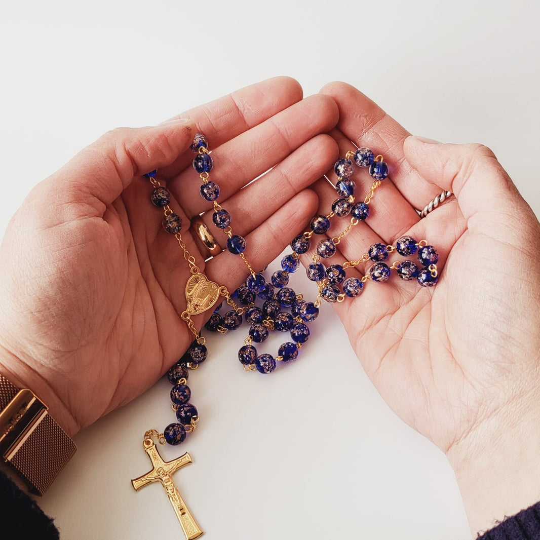 Blue Murano glass rosary held in two open hands